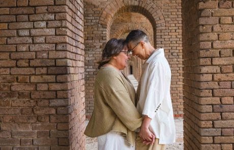Wedding Dry Tortugas Two people holding hands and pressing their foreheads together, smiling near a brick archway, during their inclusive wedding planning in Key West.