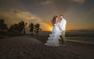 Couple in wedding attire embracing on a Key West beach at sunrise during their intimate Wedding ceremony. Key West Florida