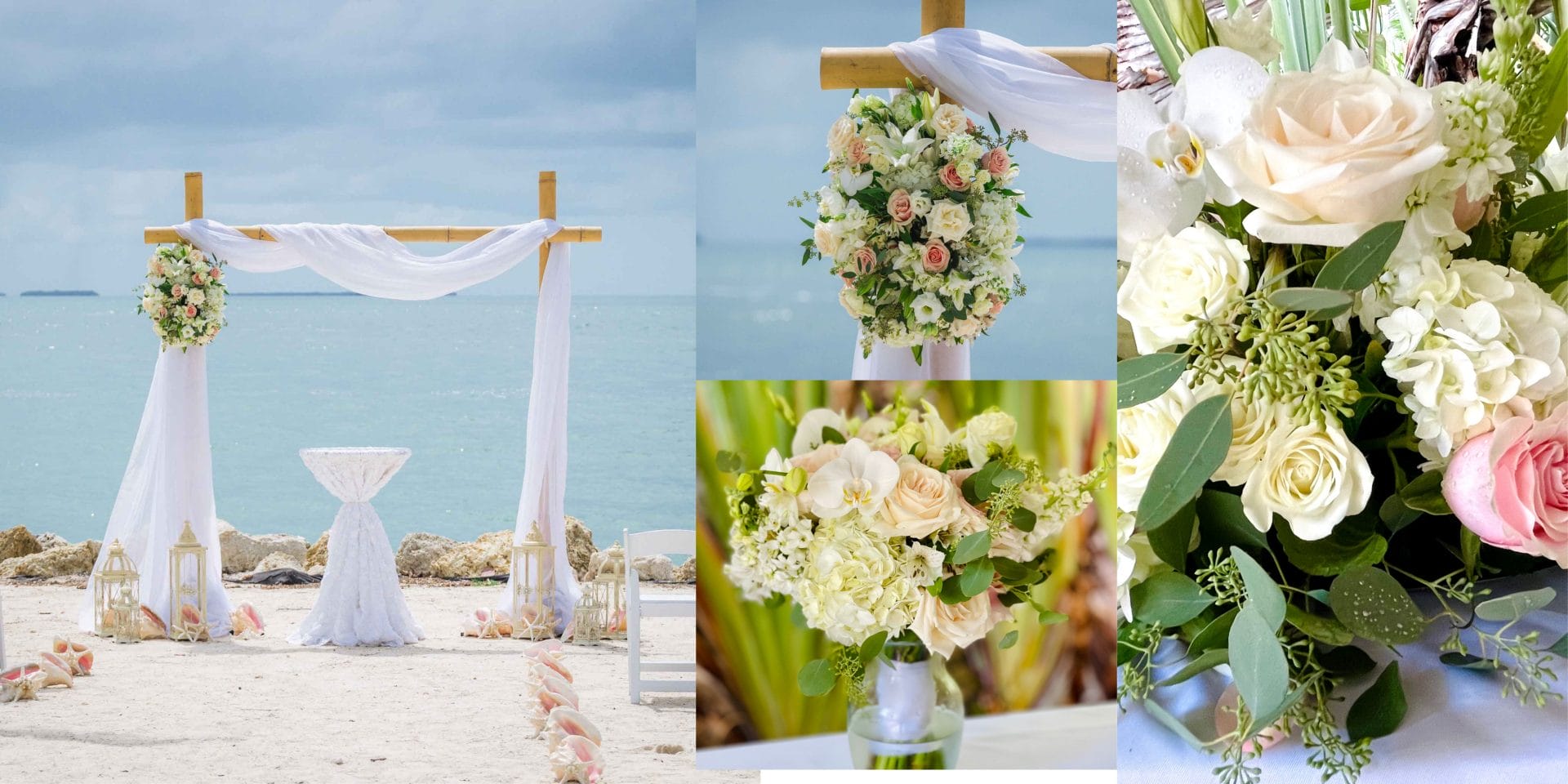 A beach wedding setup with a floral arch, a small table on the sand, and flower arrangements featuring white and pink roses. The sea is in the background.